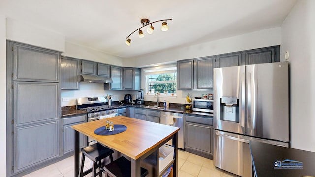 554 Foxford Rd, Bartlett, IL 60103 - kitchen with appliances with stainless steel finishes, dark countertops, under cabinet range hood, and light tile patterned floors
