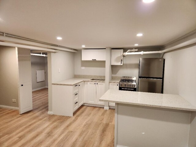 5128 W Carmen Ave, Chicago, IL 60630 - kitchen featuring stainless steel appliances, light wood-type flooring, recessed lighting, white cabinets, and light stone counters
