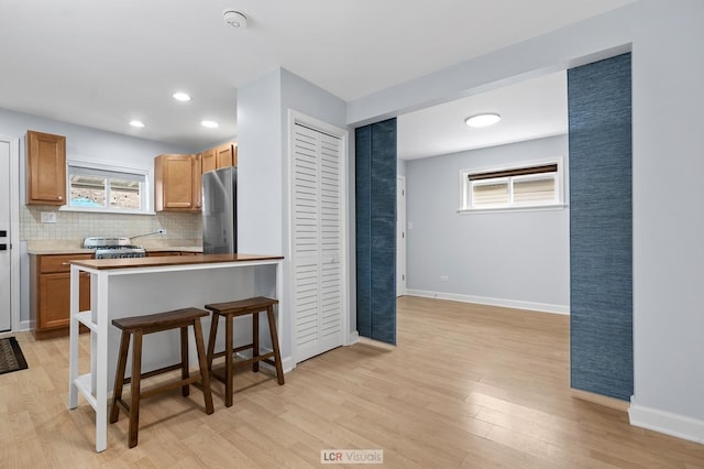 5128 W Carmen Ave, Chicago, IL 60630 - kitchen with freestanding refrigerator, light wood-style flooring, range, a kitchen bar, and backsplash