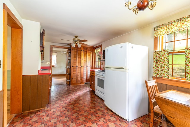 244 S Division St, Galena, IL 61036 - kitchen featuring white appliances, ceiling fan, brick patterned floors, a chandelier, and wooden walls