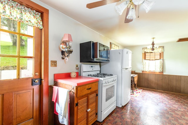 244 S Division St, Galena, IL 61036 - kitchen with white appliances, a chandelier, a ceiling fan, wooden walls, and wainscoting