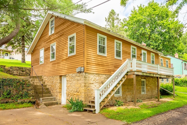 244 S Division St, Galena, IL 61036 - view of front facade featuring stairway, concrete driveway, a wooden deck, and stone siding