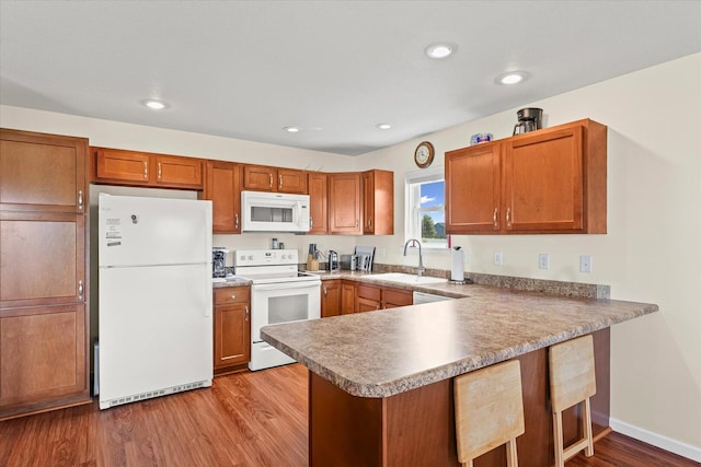 209A Evergreen St, Gifford, IL 61847 - kitchen with white appliances, a peninsula, light wood-type flooring, brown cabinets, and a kitchen breakfast bar