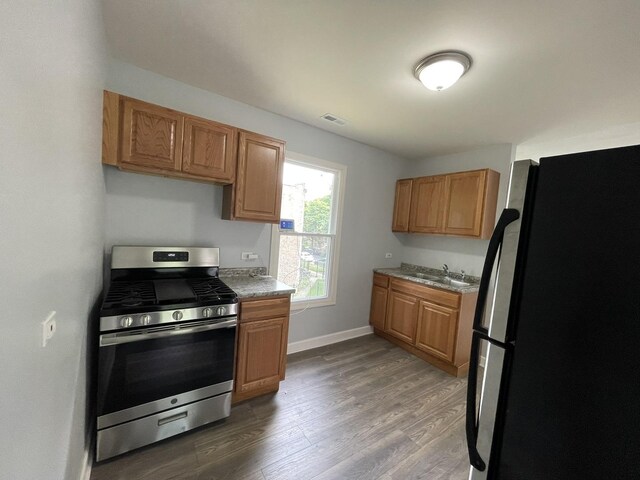 7948 S Union Ave, Chicago, IL 60620 - kitchen with freestanding refrigerator, stainless steel gas range, wood finished floors, and brown cabinetry