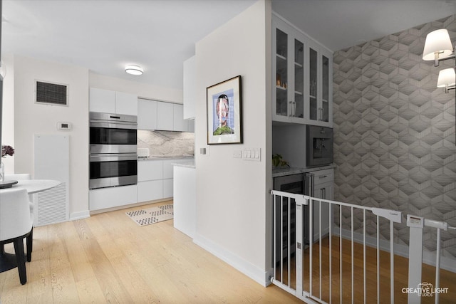 1410 N State Pkwy Unit 5B, Chicago, IL 60610 - kitchen with double oven, beverage cooler, white cabinets, glass insert cabinets, and light wood finished floors