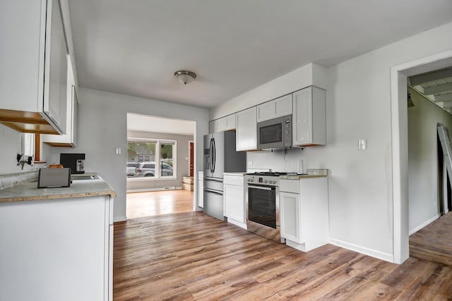 730 E 156th St, South Holland, IL 60473 - kitchen with appliances with stainless steel finishes, light wood finished floors, light countertops, and white cabinetry