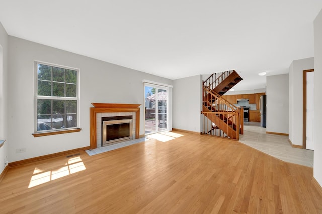 15 Harrison Ln, Streamwood, IL 60107 - unfurnished living room with a tiled fireplace, stairway, and light wood-style floors