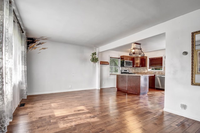 7912 S 85th Ave, Justice, IL 60458 - kitchen featuring stainless steel appliances, light countertops, dark wood-style floors, a kitchen island, and open floor plan