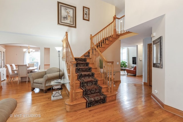 2578 Crestview Dr, Aurora, IL 60502 - stairs featuring arched walkways, a chandelier, a towering ceiling, and wood finished floors