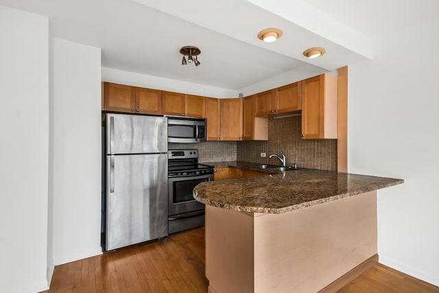 1360 N Sandburg Ter Unit 703C, Chicago, IL 60610 - kitchen with appliances with stainless steel finishes, a peninsula, tasteful backsplash, hardwood / wood-style flooring, and dark stone countertops