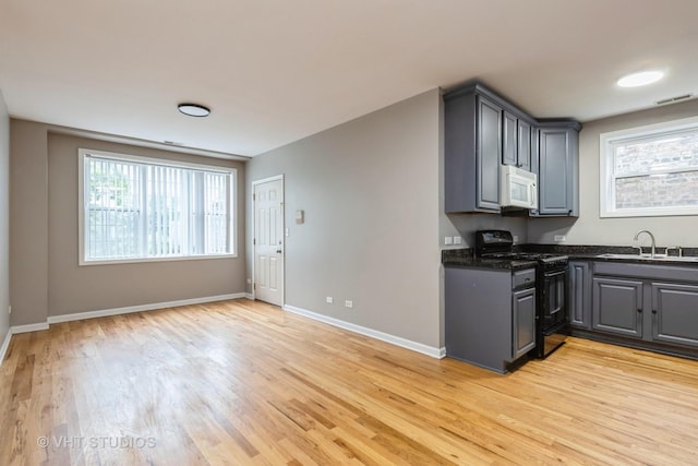 3115 W Lexington St, Chicago, IL 60612 - kitchen with black gas range, white microwave, light wood finished floors, gray cabinets, and dark stone countertops