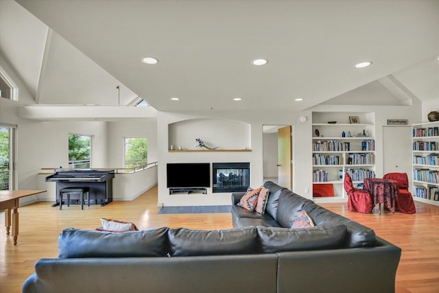2405 Prairieridge Pl, Champaign, IL 61822 - living area featuring healthy amount of natural light, a fireplace with flush hearth, wood finished floors, lofted ceiling, and built in shelves
