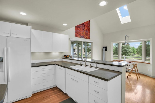 2405 Prairieridge Pl, Champaign, IL 61822 - kitchen with white appliances, a peninsula, dark countertops, light wood finished floors, and a skylight