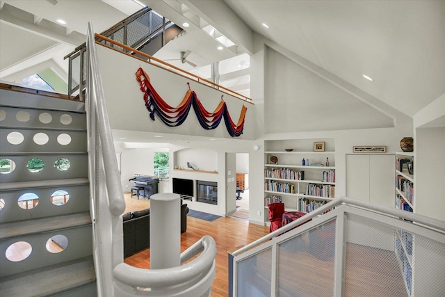 2405 Prairieridge Pl, Champaign, IL 61822 - staircase with a towering ceiling, wood finished floors, built in shelves, a glass covered fireplace, and healthy amount of natural light