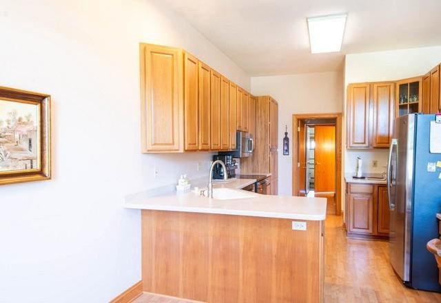 9000 226th Ct Unit 23B, Salem, WI 53168 - kitchen with stainless steel appliances, a peninsula, light countertops, light wood-style floors, and glass insert cabinets