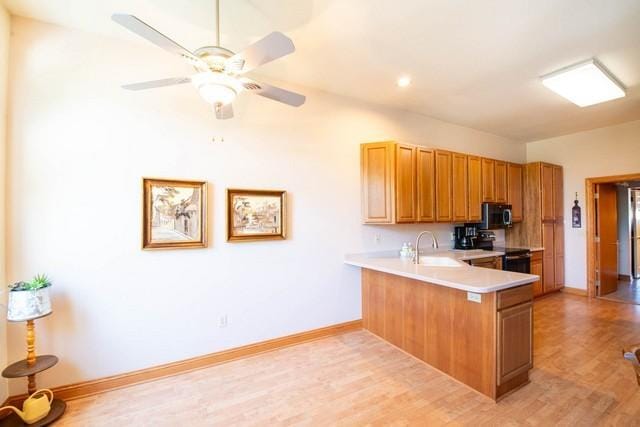 9000 226th Ct Unit 23B, Salem, WI 53168 - kitchen with black electric range, stainless steel microwave, a peninsula, light wood finished floors, and light countertops
