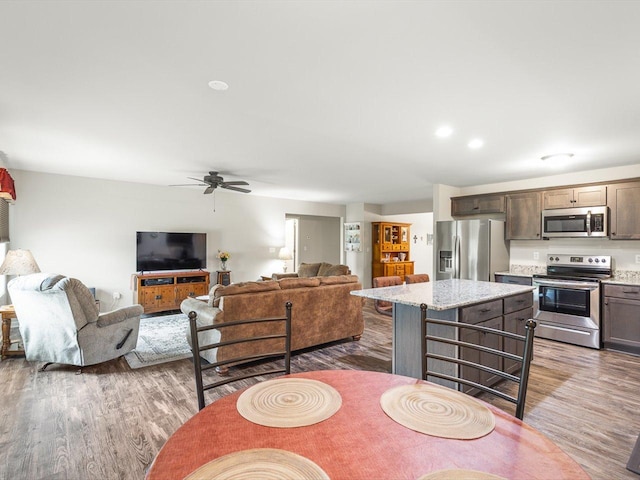 4122 Waters Edge Dr, Belvidere, IL 61008 - kitchen with appliances with stainless steel finishes, wood finished floors, a ceiling fan, and a kitchen island