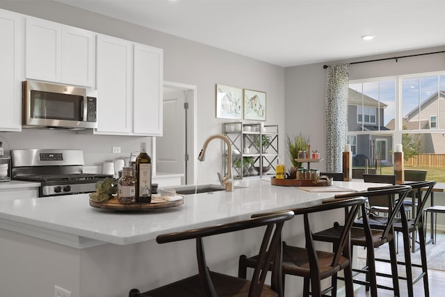 614 Lismore Cir, Elgin, IL 60124 - kitchen featuring appliances with stainless steel finishes, white cabinets, light stone counters, a breakfast bar, and recessed lighting