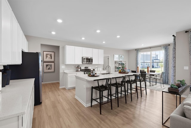 614 Lismore Cir, Elgin, IL 60124 - kitchen featuring appliances with stainless steel finishes, light wood-style flooring, a kitchen breakfast bar, recessed lighting, and white cabinetry