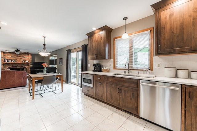 1132 Swanberg Ct, Sycamore, IL 60178 - kitchen featuring appliances with stainless steel finishes, light countertops, a brick fireplace, ceiling fan, and dark brown cabinetry