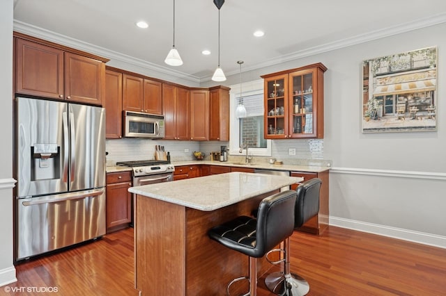 2438 N Clybourn Ave Unit 2, Chicago, IL 60614 - kitchen with appliances with stainless steel finishes, dark wood-style flooring, a breakfast bar, glass insert cabinets, and ornamental molding