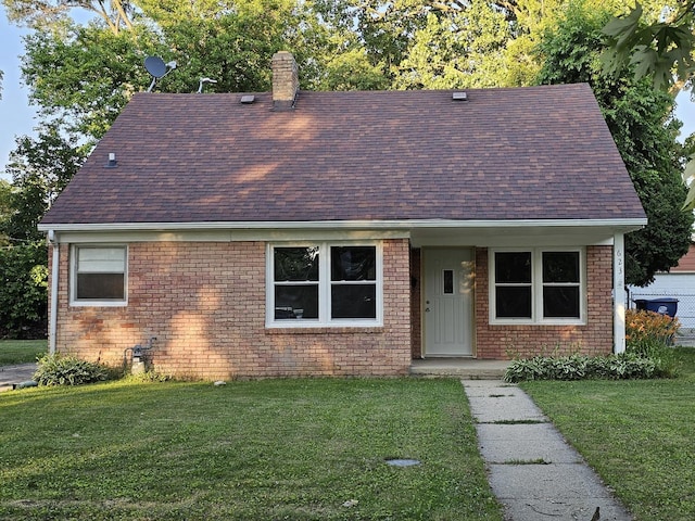 623 Westmoreland Ave, Waukegan, IL 60085 - view of front facade with a shingled roof, a front lawn, a chimney, and brick siding