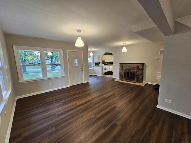 623 Westmoreland Ave, Waukegan, IL 60085 - unfurnished living room with arched walkways, dark wood-style flooring, and a stone fireplace
