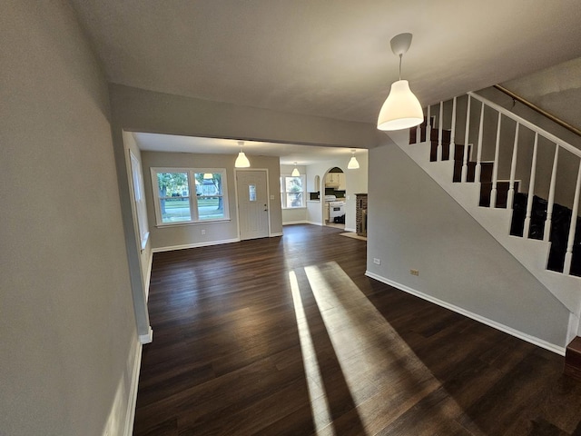 623 Westmoreland Ave, Waukegan, IL 60085 - unfurnished living room with arched walkways, dark wood-style floors, and stairway
