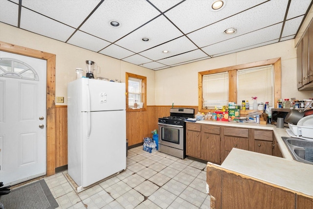 2142 N Mobile Ave, Chicago, IL 60639 - kitchen with freestanding refrigerator, stainless steel gas range oven, a wainscoted wall, a paneled ceiling, and wood walls
