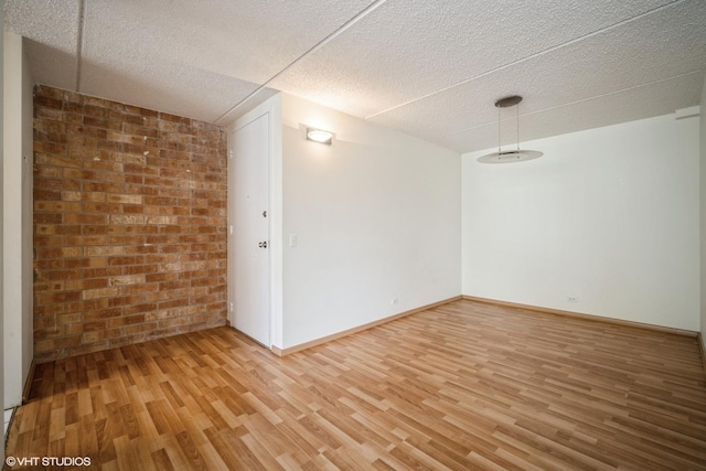 2020 St Johns Ave Unit 309, Highland Park, IL 60035 - spare room with light wood-style flooring, brick wall, and a textured ceiling