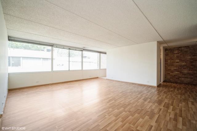 2020 St Johns Ave Unit 309, Highland Park, IL 60035 - spare room with light wood-style flooring, a textured ceiling, and brick wall