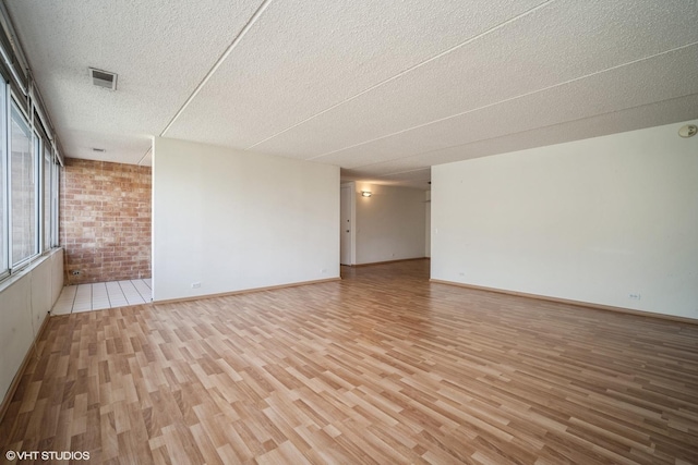 2020 St Johns Ave Unit 309, Highland Park, IL 60035 - empty room featuring light wood-type flooring, a textured ceiling, and brick wall