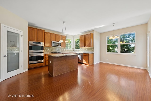 805 W Mystic Ln, Romeoville, IL 60446 - kitchen with stainless steel appliances, dark wood-type flooring, a chandelier, tasteful backsplash, and brown cabinetry