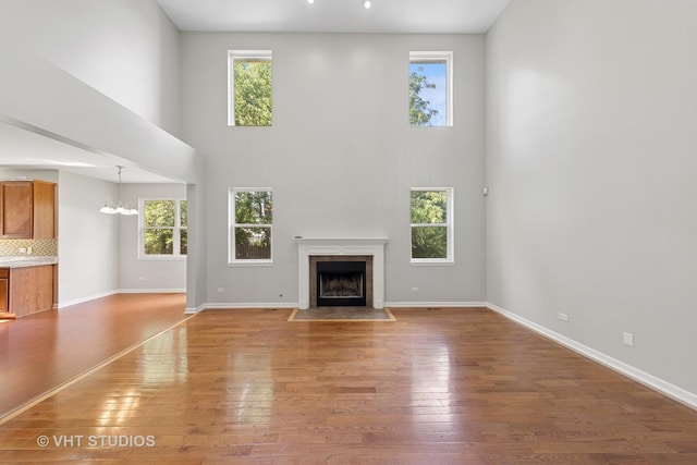 805 W Mystic Ln, Romeoville, IL 60446 - unfurnished living room with plenty of natural light, a towering ceiling, a fireplace with flush hearth, and wood finished floors