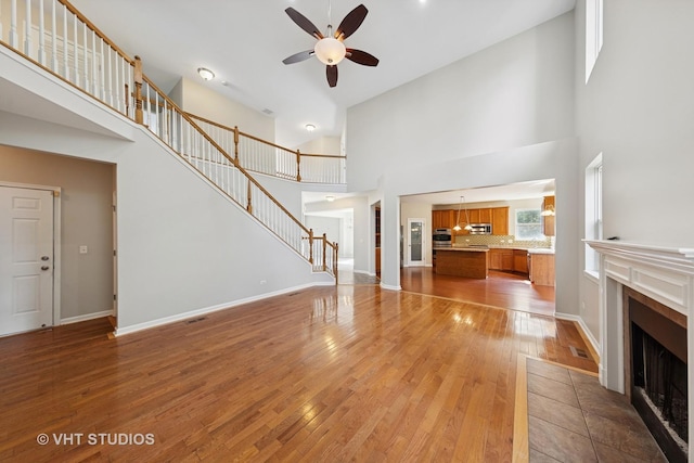 805 W Mystic Ln, Romeoville, IL 60446 - unfurnished living room with high vaulted ceiling, a fireplace, ceiling fan, light wood finished floors, and stairs