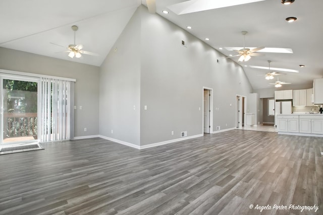 1803 N Woodlawn Park Ave, Mchenry, IL 60051 - unfurnished living room featuring ceiling fan, high vaulted ceiling, a skylight, light wood-style floors, and recessed lighting