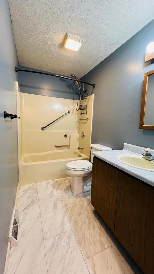 113 E Seminole St, Dwight, IL 60420 - bathroom featuring shower / tub combination, a textured ceiling, vanity, and marble look tiles