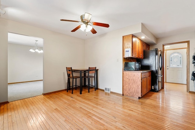 7340 Mimosa Dr, Orland Park, IL 60462 - kitchen with black appliances, brown cabinets, light wood-type flooring, ceiling fan, and a chandelier