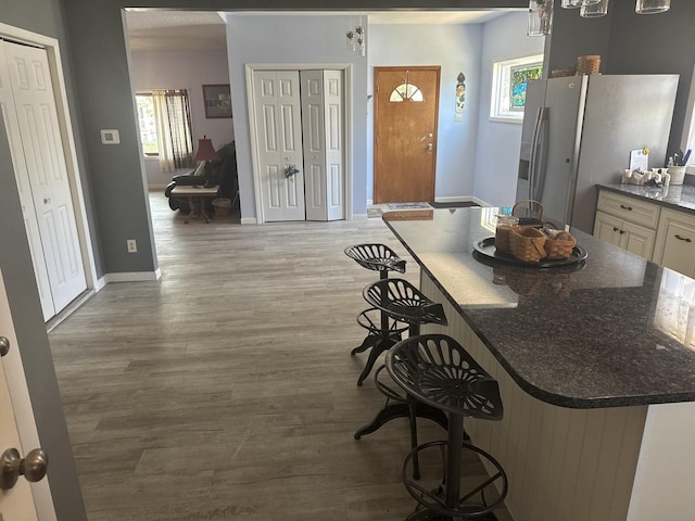 600 W White St, Clinton, IL 61727 - kitchen featuring white fridge with ice dispenser, wood finished floors, a kitchen breakfast bar, and healthy amount of natural light