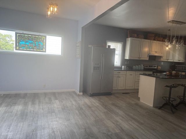 600 W White St, Clinton, IL 61727 - kitchen with stainless steel appliances, dark countertops, light wood finished floors, a breakfast bar, and decorative light fixtures