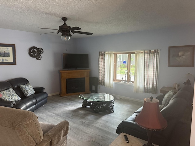600 W White St, Clinton, IL 61727 - living room with wood finished floors, a fireplace, ceiling fan, and a textured ceiling