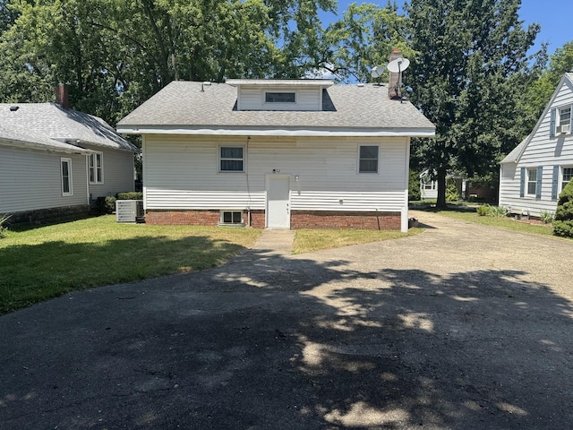 600 W White St, Clinton, IL 61727 - back of house featuring roof with shingles, a yard, a chimney, and driveway