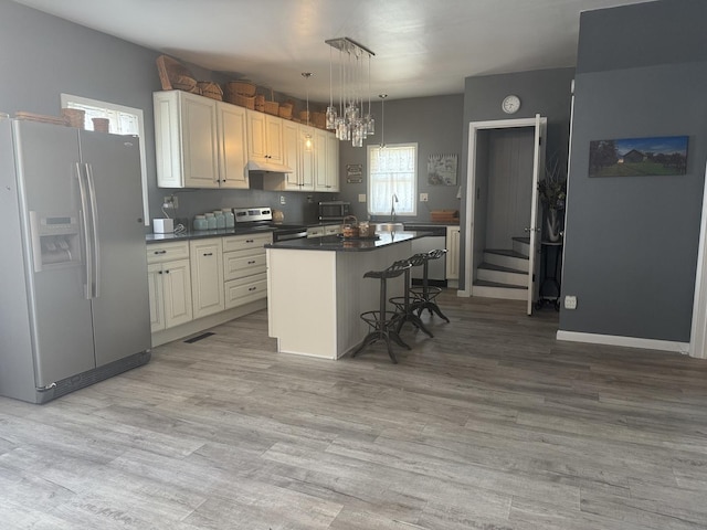 600 W White St, Clinton, IL 61727 - kitchen with white fridge with ice dispenser, dark countertops, stainless steel electric stove, a kitchen breakfast bar, and a chandelier