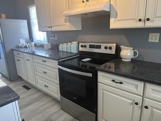 600 W White St, Clinton, IL 61727 - kitchen with appliances with stainless steel finishes, under cabinet range hood, white cabinetry, light wood-type flooring, and dark stone countertops