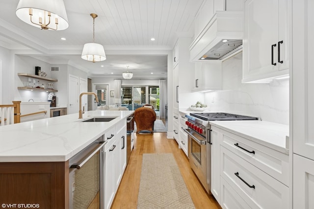 823 W George St Unit 1, Chicago, IL 60657 - kitchen featuring range with two ovens, premium range hood, light wood finished floors, a kitchen island with sink, and white cabinets