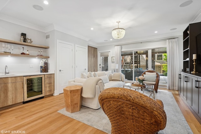 823 W George St Unit 1, Chicago, IL 60657 - living area featuring wine cooler, bar with sink, light wood finished floors, ornamental molding, and a chandelier