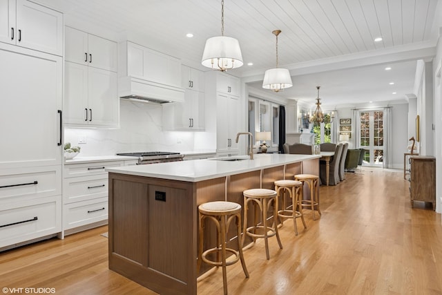 823 W George St Unit 1, Chicago, IL 60657 - kitchen with a center island with sink, white cabinets, light wood-style floors, light countertops, and decorative backsplash