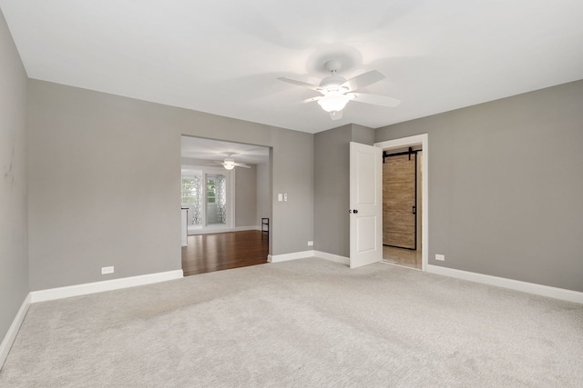 22W672 Elmwood Dr, Glen Ellyn, IL 60137 - unfurnished bedroom with light colored carpet, ceiling fan, and a barn door
