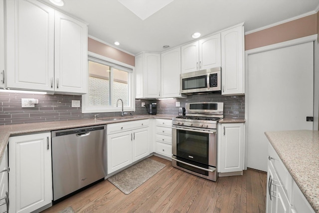 905 W Palm Dr, Mount Prospect, IL 60056 - kitchen with stainless steel appliances, crown molding, backsplash, light wood-style floors, and white cabinetry
