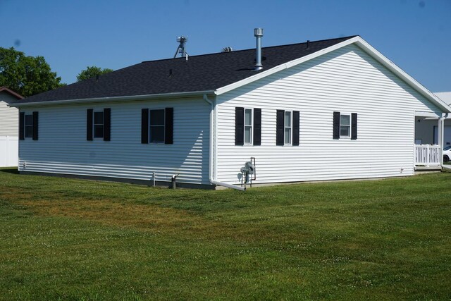 back of house with a lawn and roof with shingles